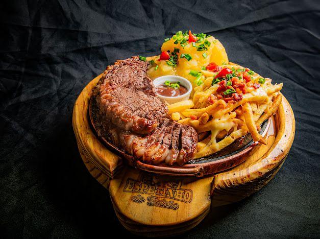Picanha grelhada com batatas, mandioca e molho servida na chapa